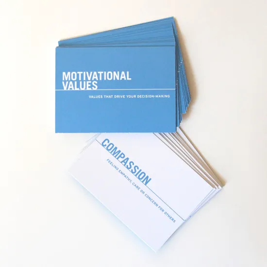 A stack of blue cards labeled Motivational Values sits above a spread of white cards, with the top card displaying Compassion and a definition in smaller text below.